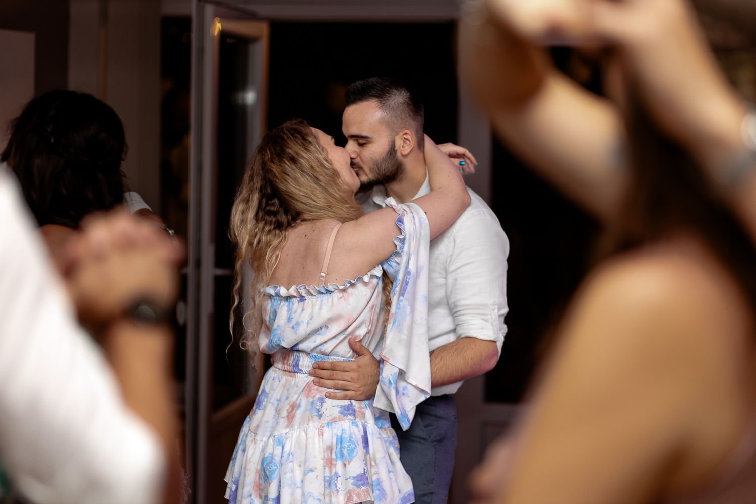 A couple shares a romantic moment in formal attire during a dimly lit evening celebration.