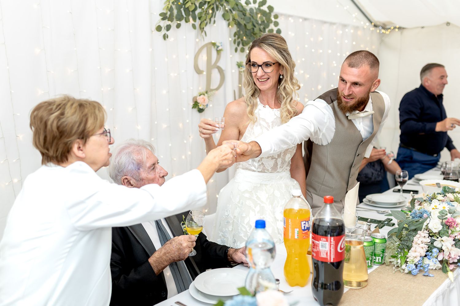 People gathered around tables at an outdoor event enjoying food and drinks during a casual dining celebration.