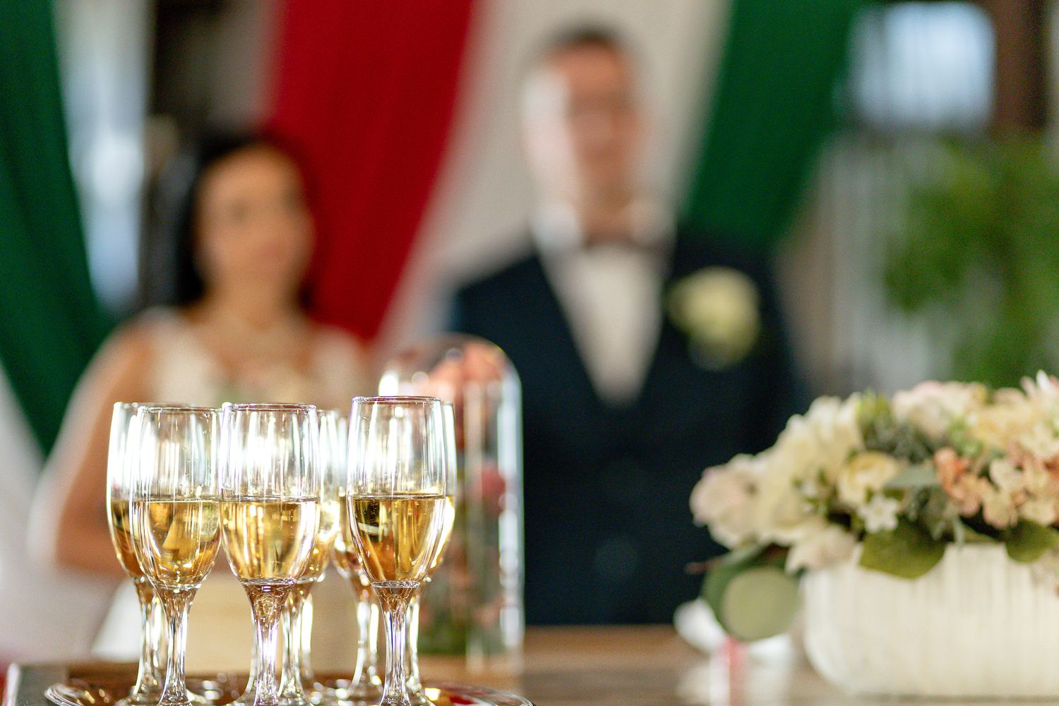 Elegant wedding reception table settings with champagne glasses, white floral centerpieces and warm candlelight.