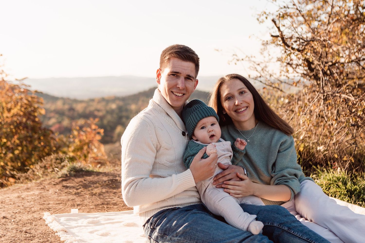 Family sharing loving moments together on blanket during autumn photoshoot.