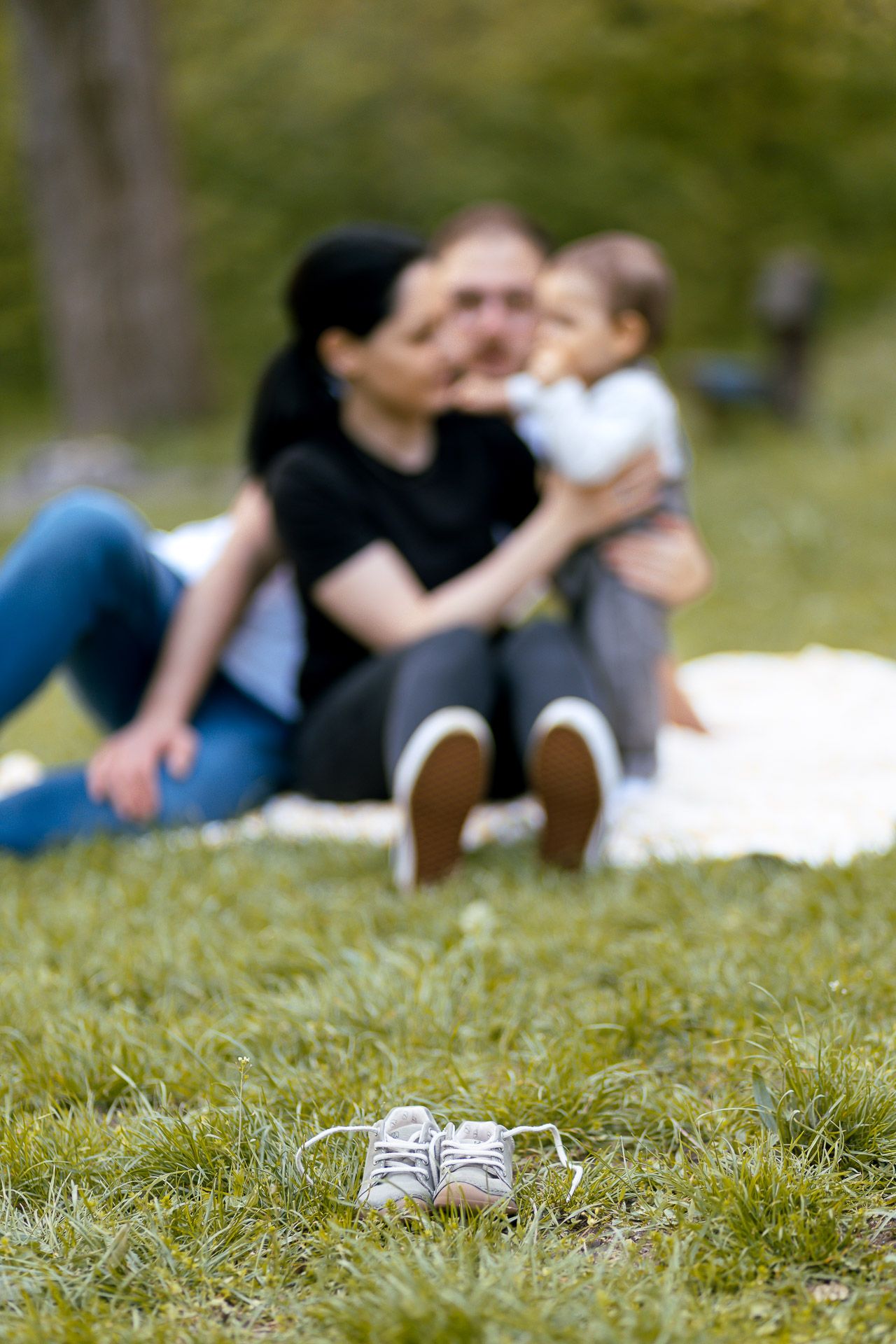 Lifestyle family photography with shoes in foreground on green grass.
