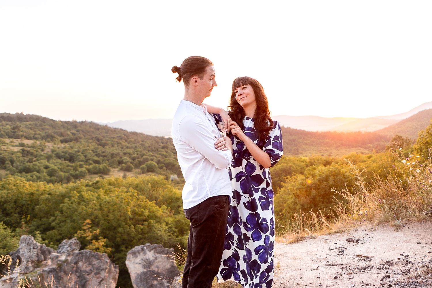 A romantic photoshoot at sunset with mountains and forest in the background.
