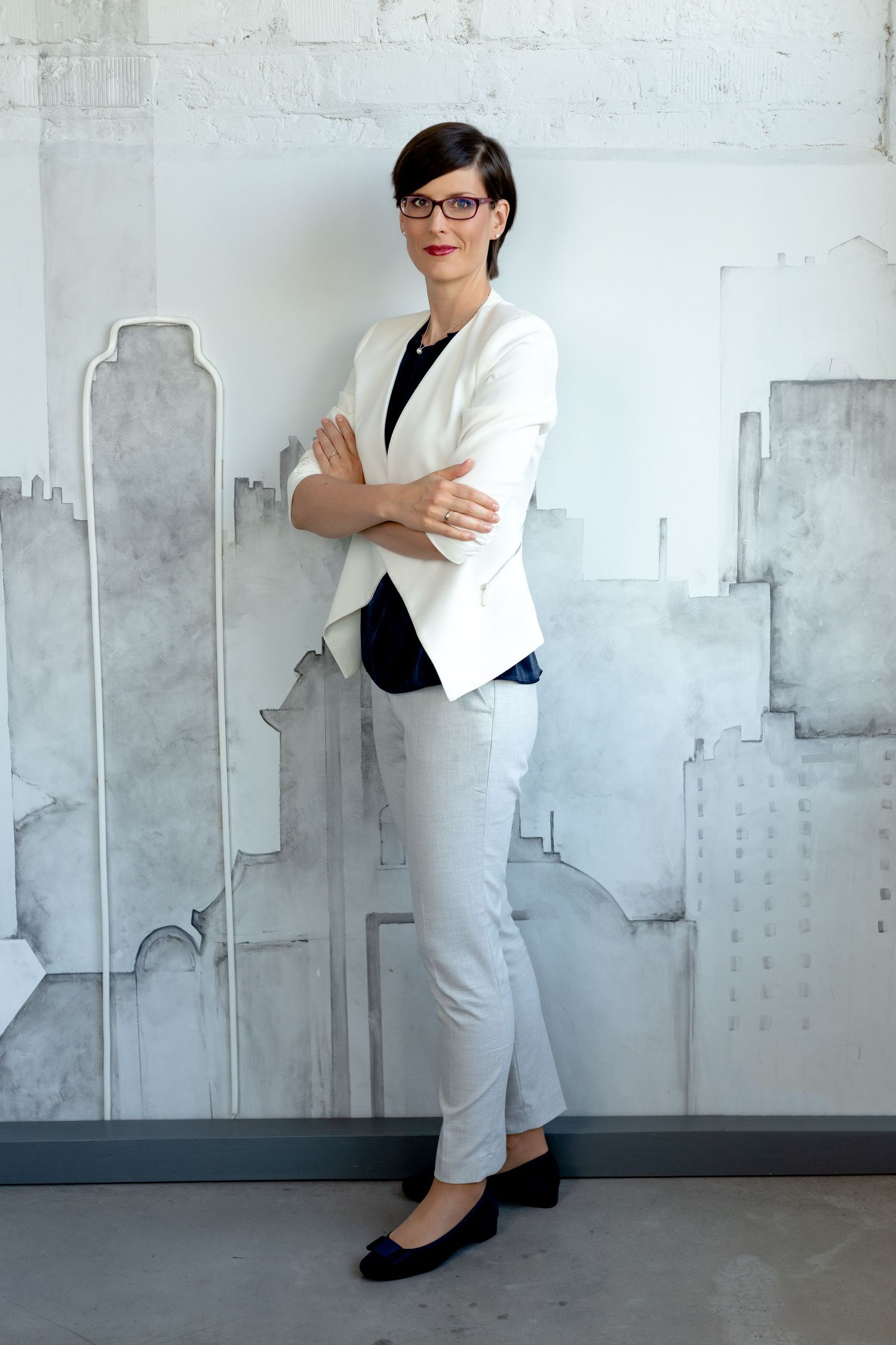 Business portrait with cityscape mural backdrop showing professional attire and confident stance.