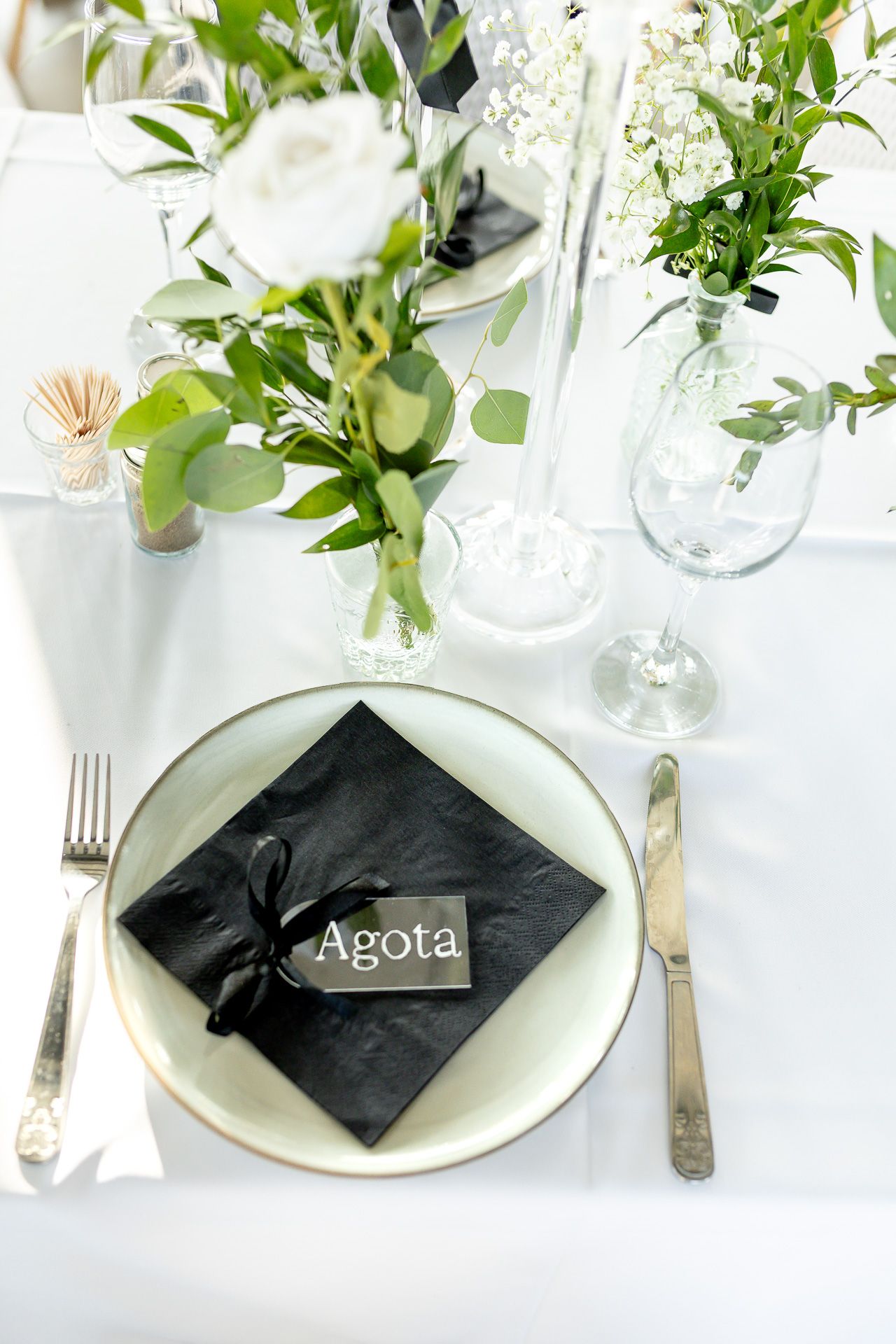 Elegant table settings with white flowers and black napkins featuring name cards.