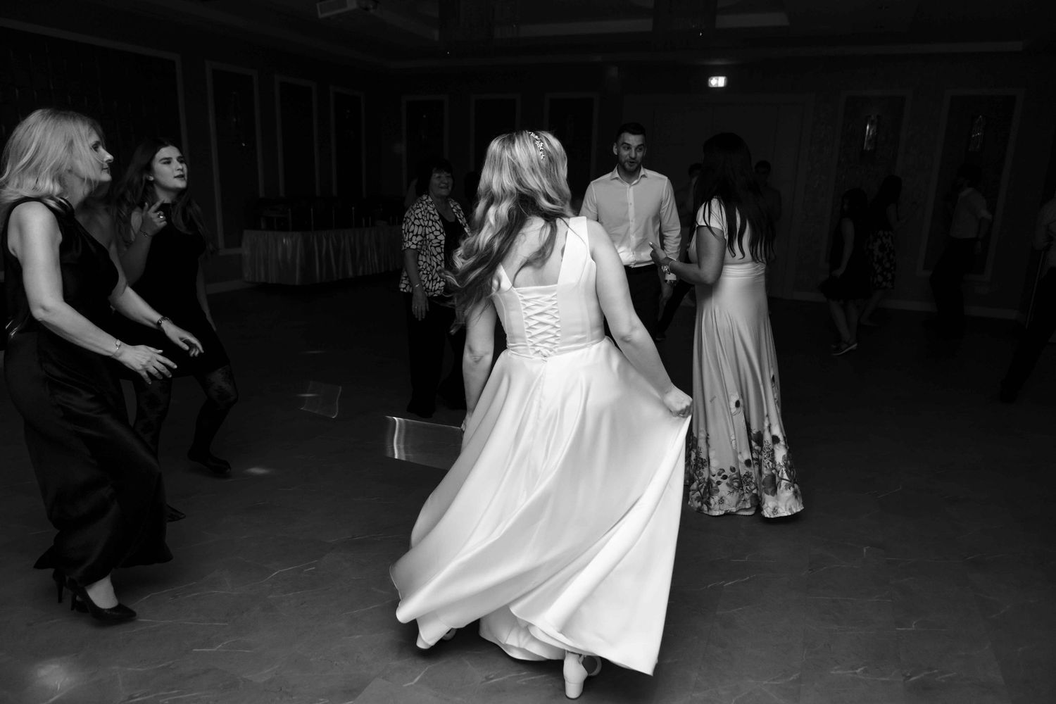 A bride twirls on the dance floor in a flowing white dress during an evening wedding reception.