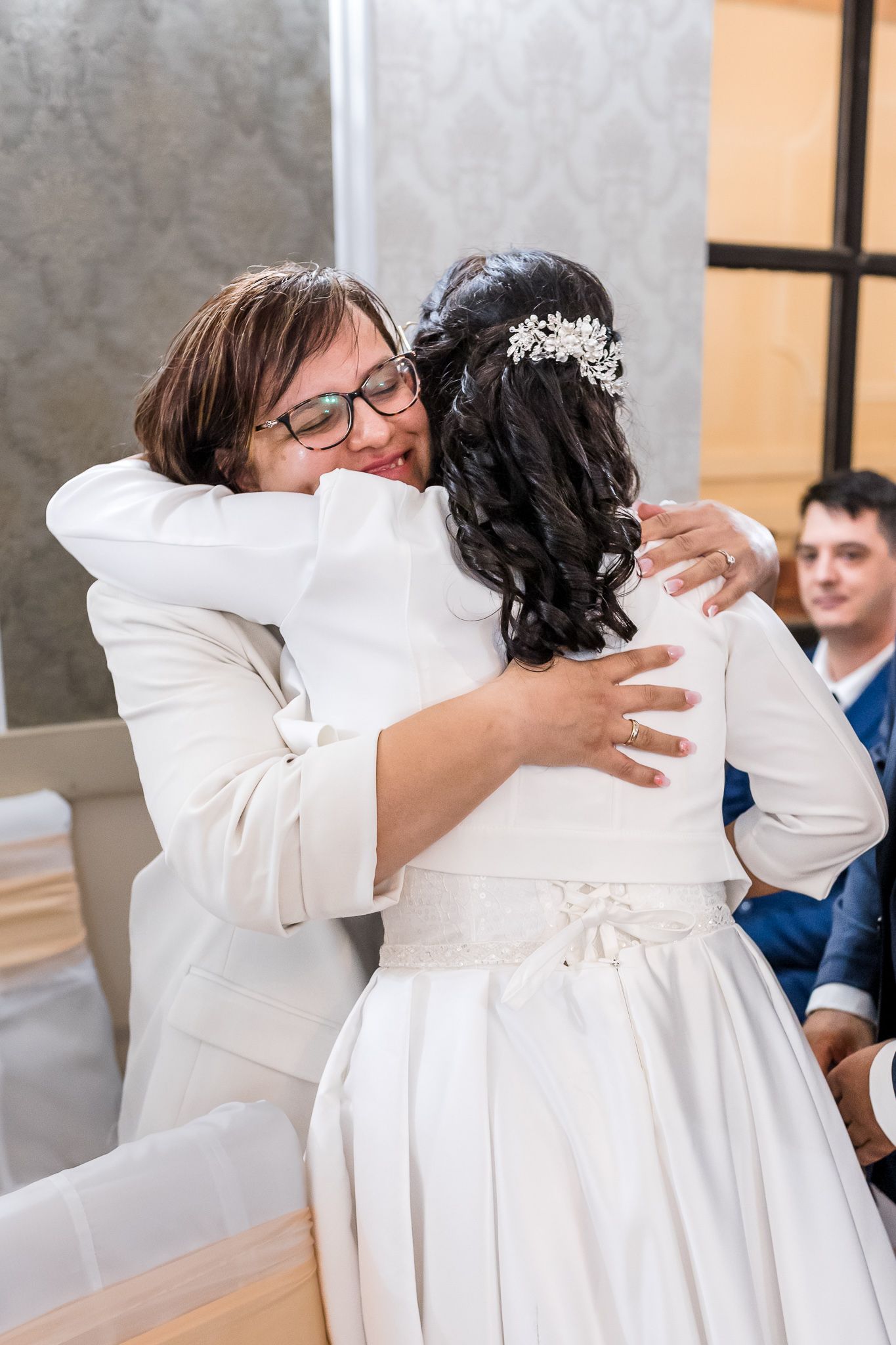 A series of photos showing a tender embrace between two people in white formal attire at a wedding ceremony.