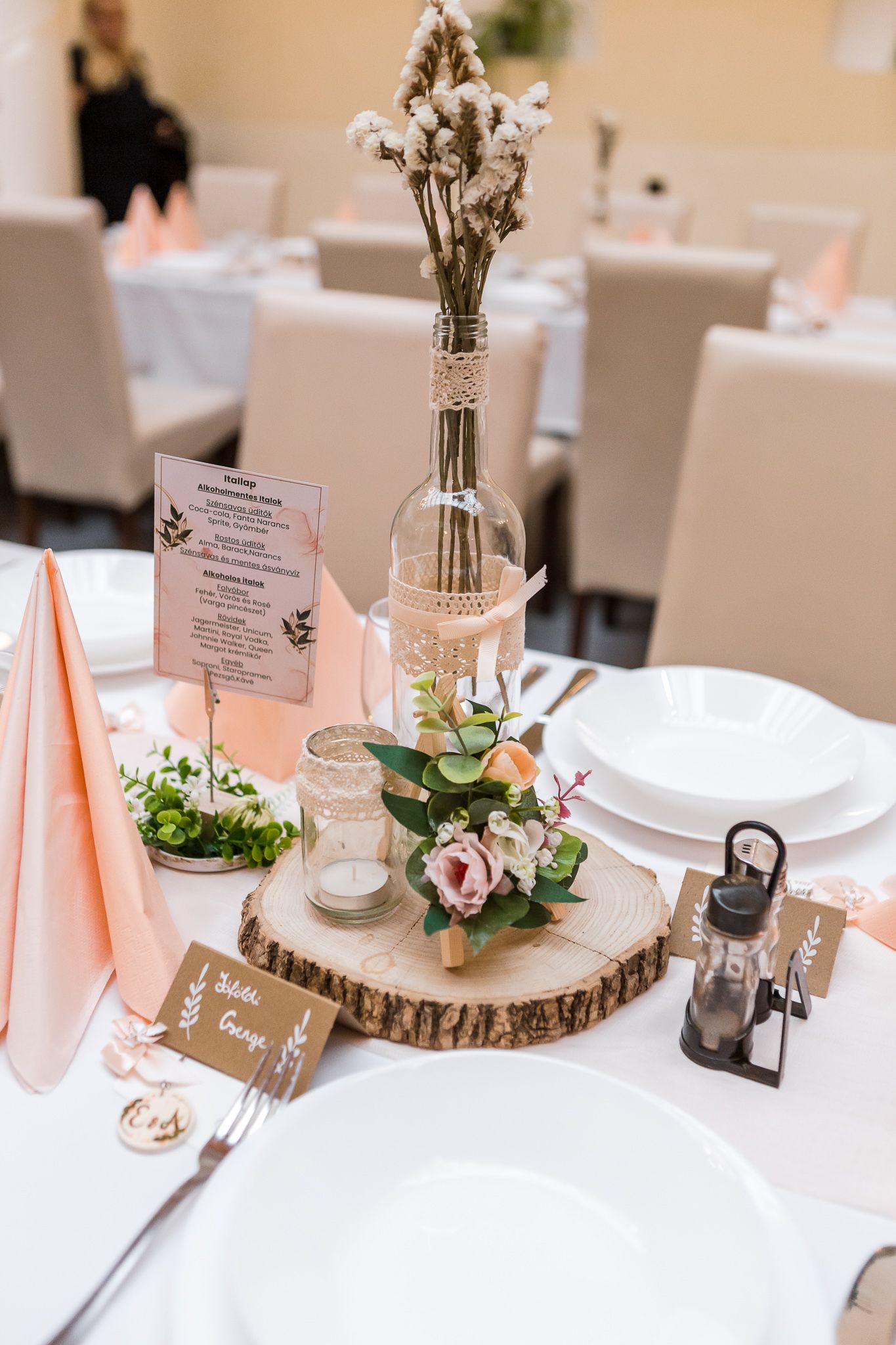 Elegant rustic wedding reception table settings with wood slice centerpieces, peach napkins, and delicate floral arrangements.