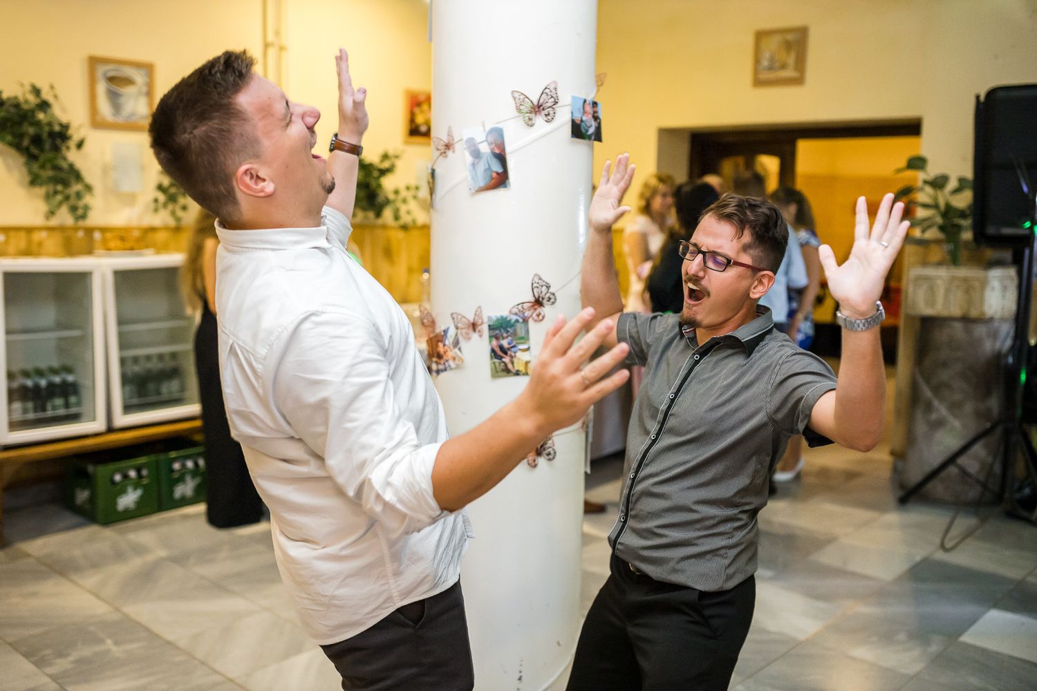 Two excited people react with energetic gestures and expressions during a lively indoor celebration.