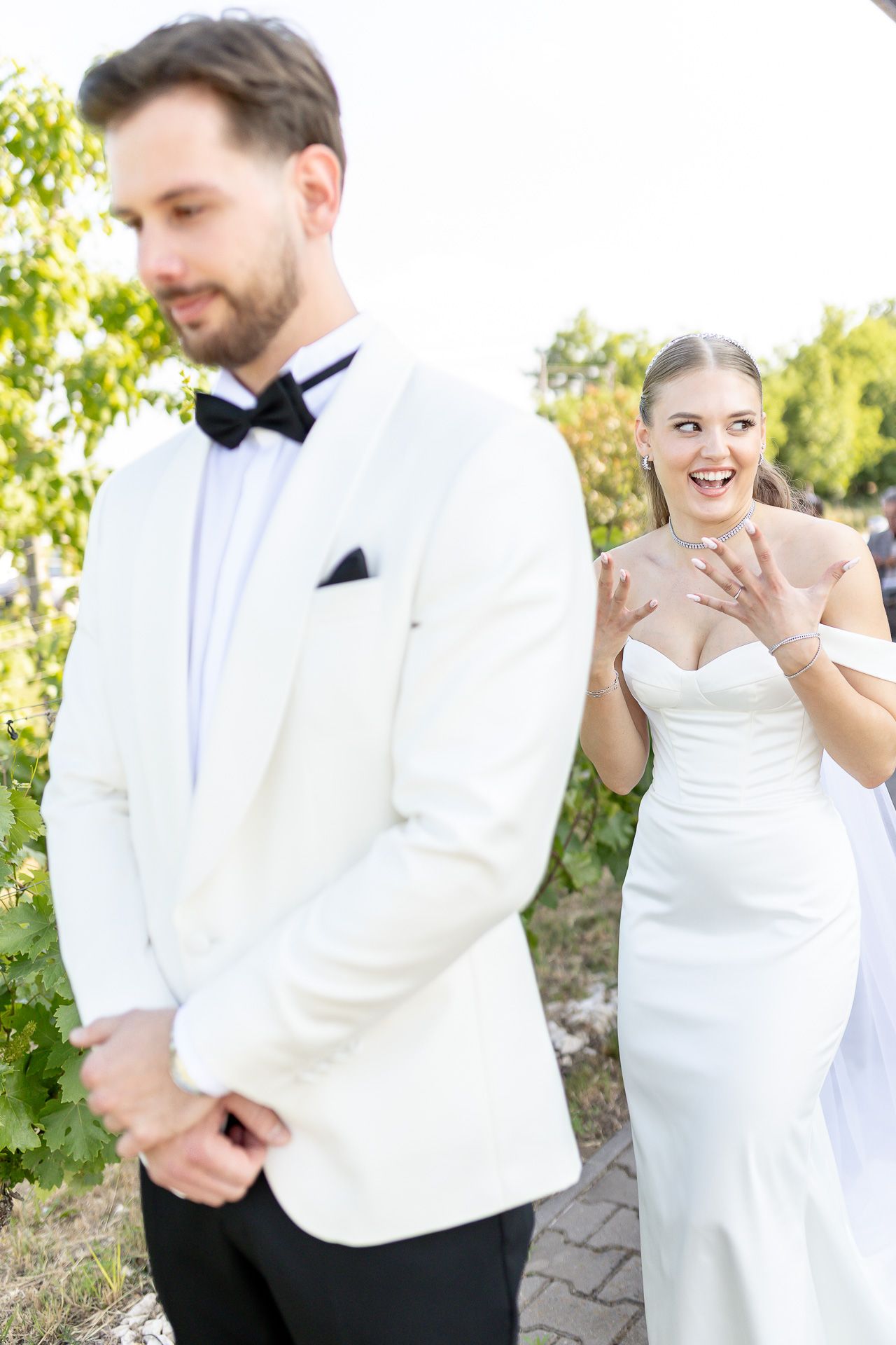 A couple shares playful moments in their wedding attire outdoors.