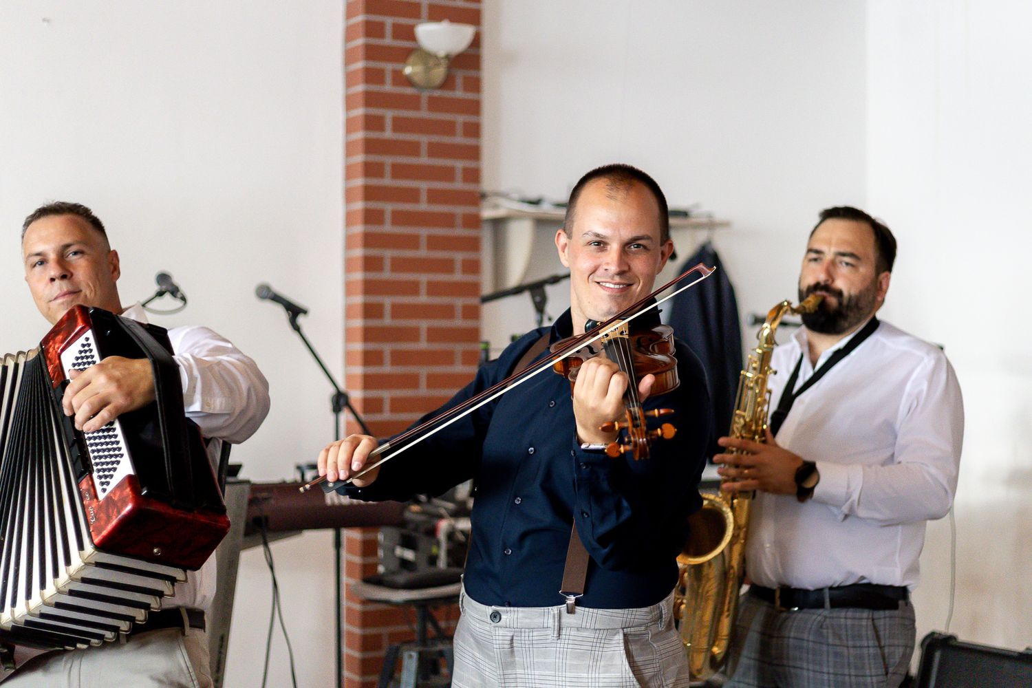 Musicians performing with saxophone, trombone and other instruments at an indoor event.