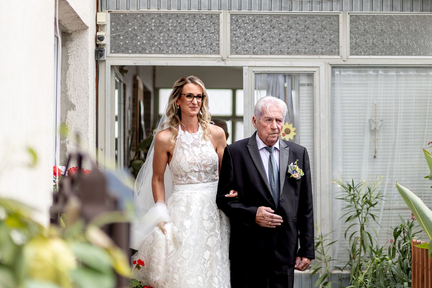 Wedding ceremony procession in an elegant greenhouse venue with white decor.