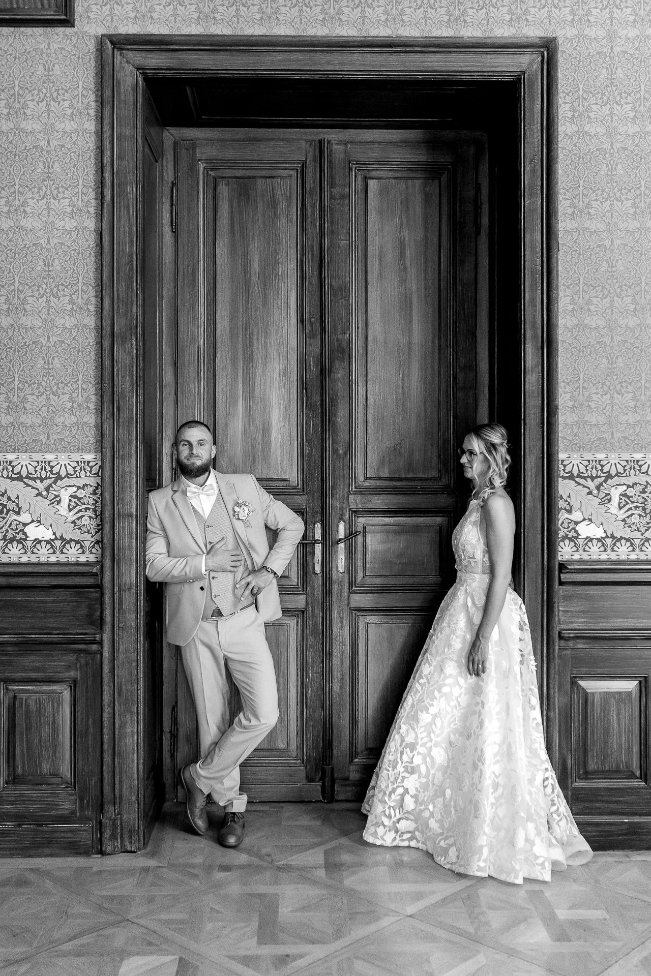 Black and white wedding photo sequence showing couple posing playfully against elegant wooden doors in vintage setting.