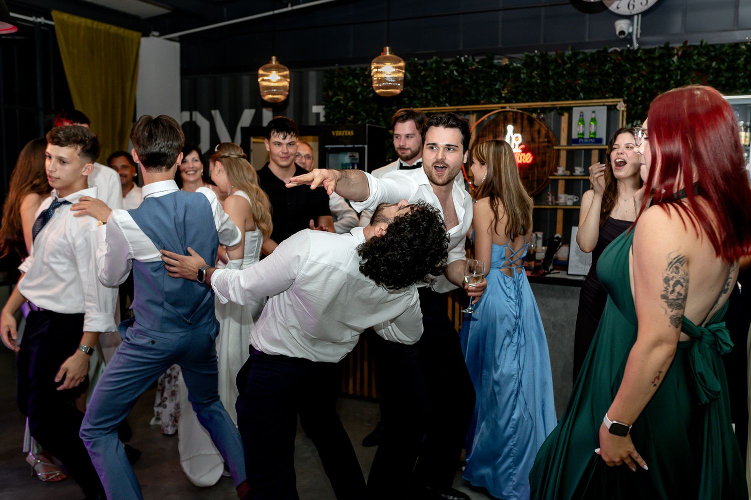 Wedding guests dancing and celebrating together on a crowded dance floor at an indoor reception.