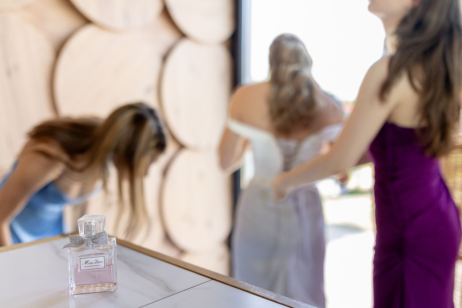 A blurred scene shows people getting ready with a perfume bottle in the foreground.