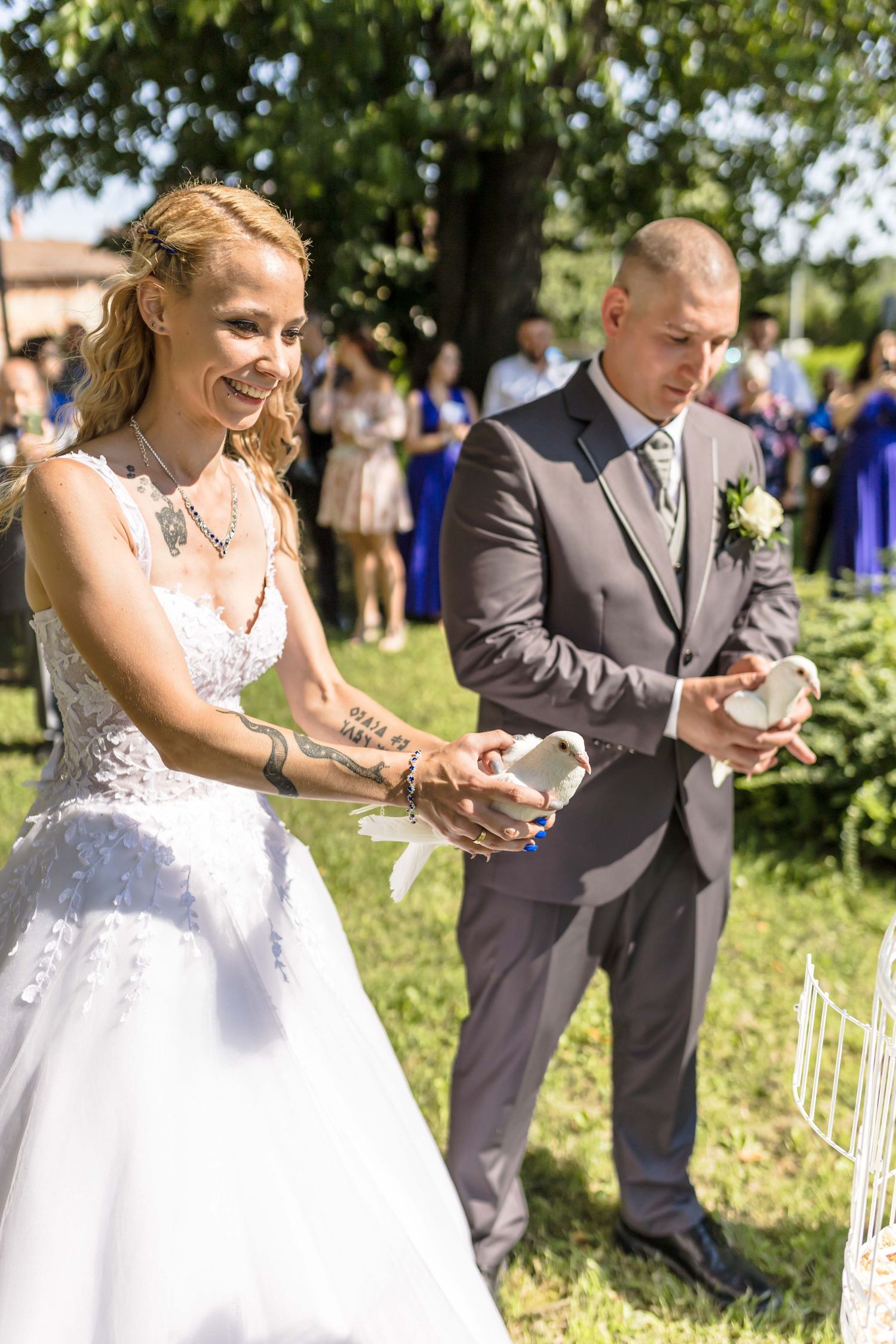 A couple in wedding attire plays a game of Jenga outdoors during their garden reception celebration.
