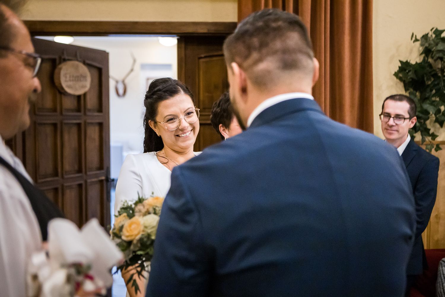 A bride and groom share a joyful moment during their wedding ceremony in an elegant indoor venue.
