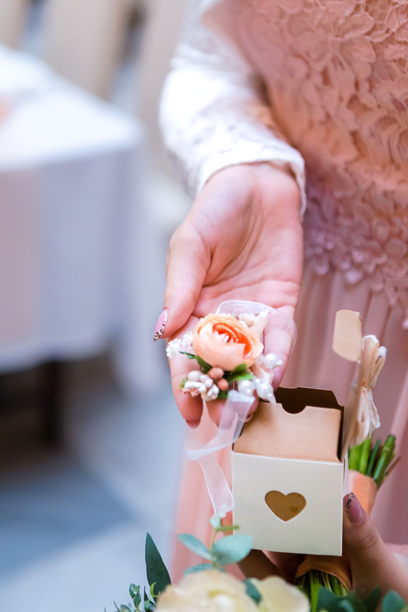 Hands opening a small wooden box with delicate floral decorations and white flowers inside.