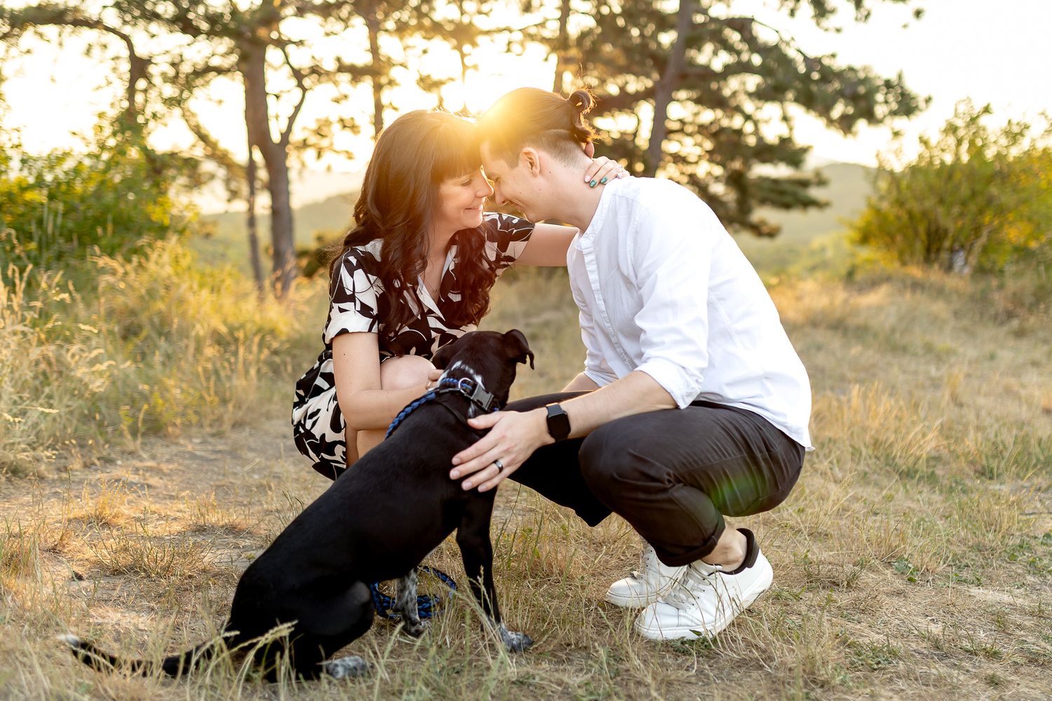 A couple relaxes on a hillside during a golden sunset photoshoot.