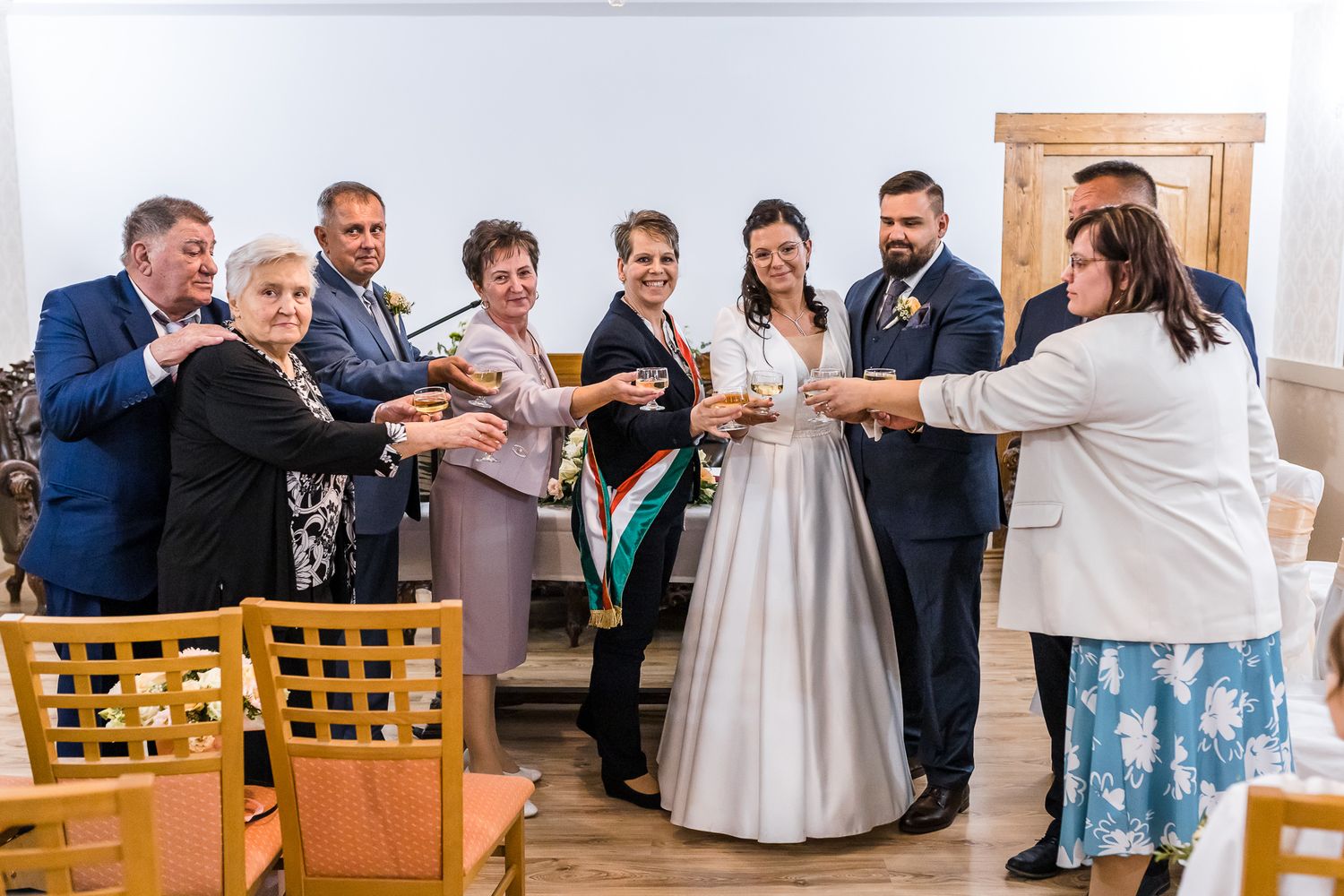 A wedding party dances and celebrates during a joyful reception at an indoor venue.