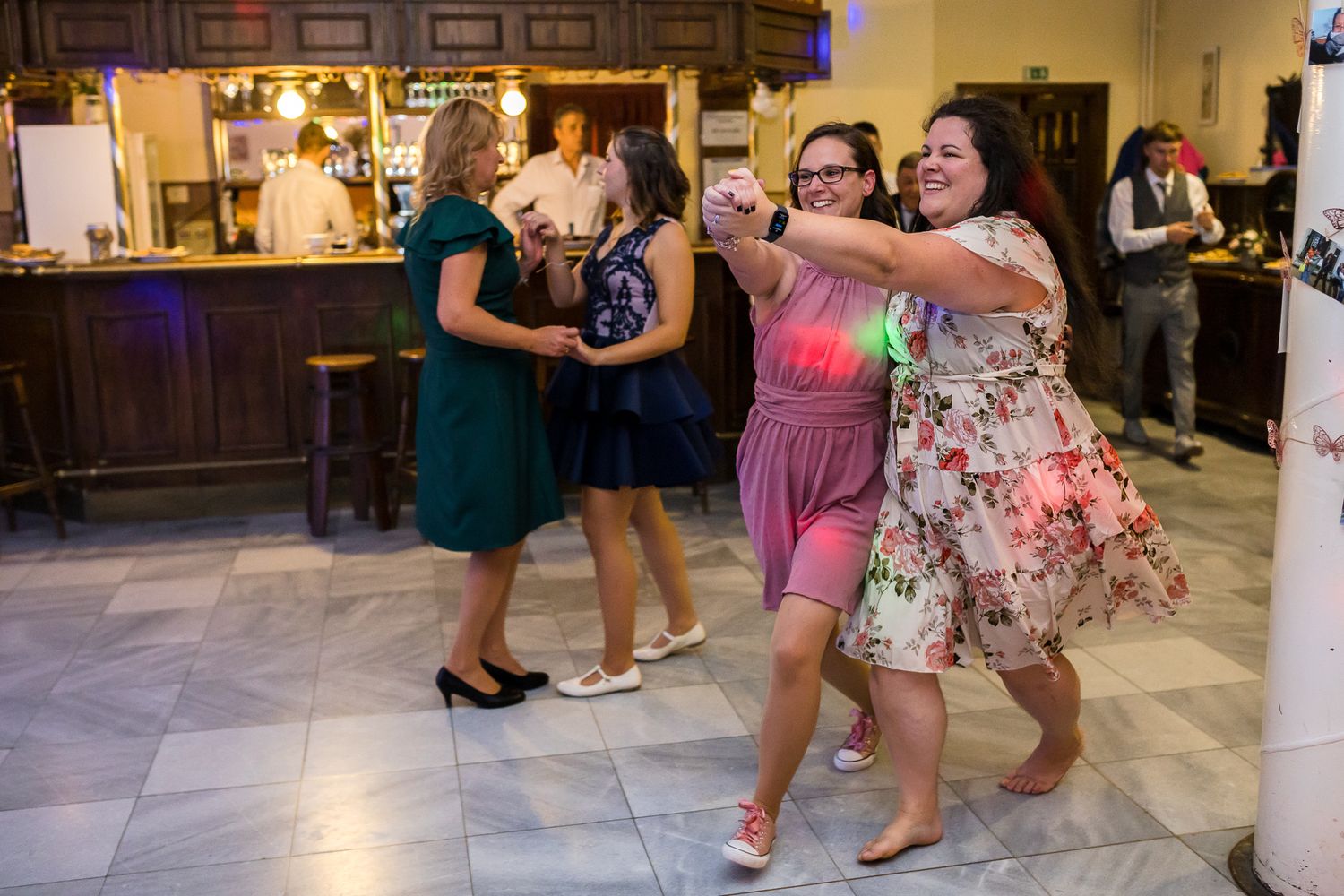 People dance and celebrate at a wedding reception in a banquet hall.