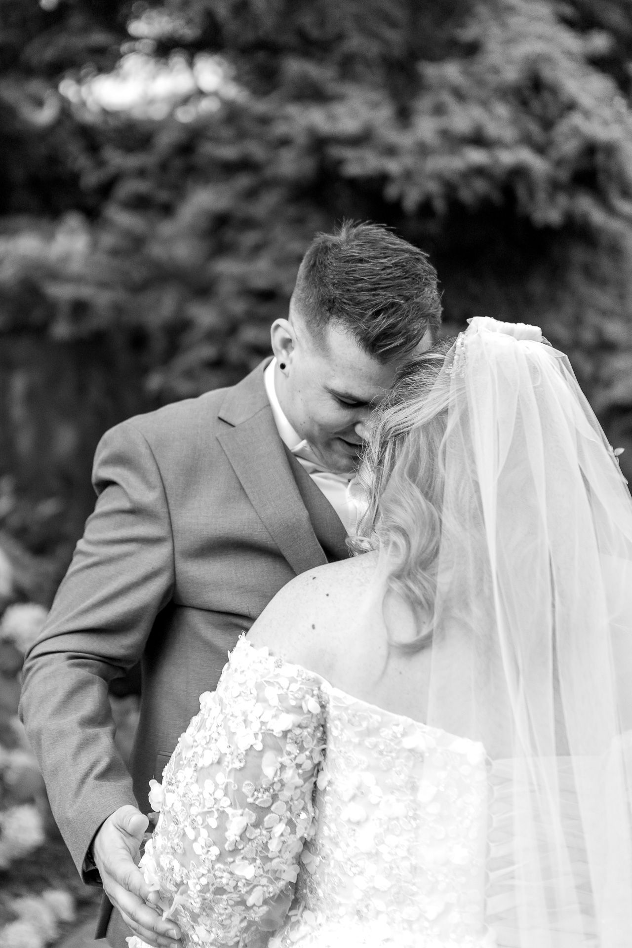A romantic wedding couple shares intimate kisses in a series of black and white photographs outdoors.