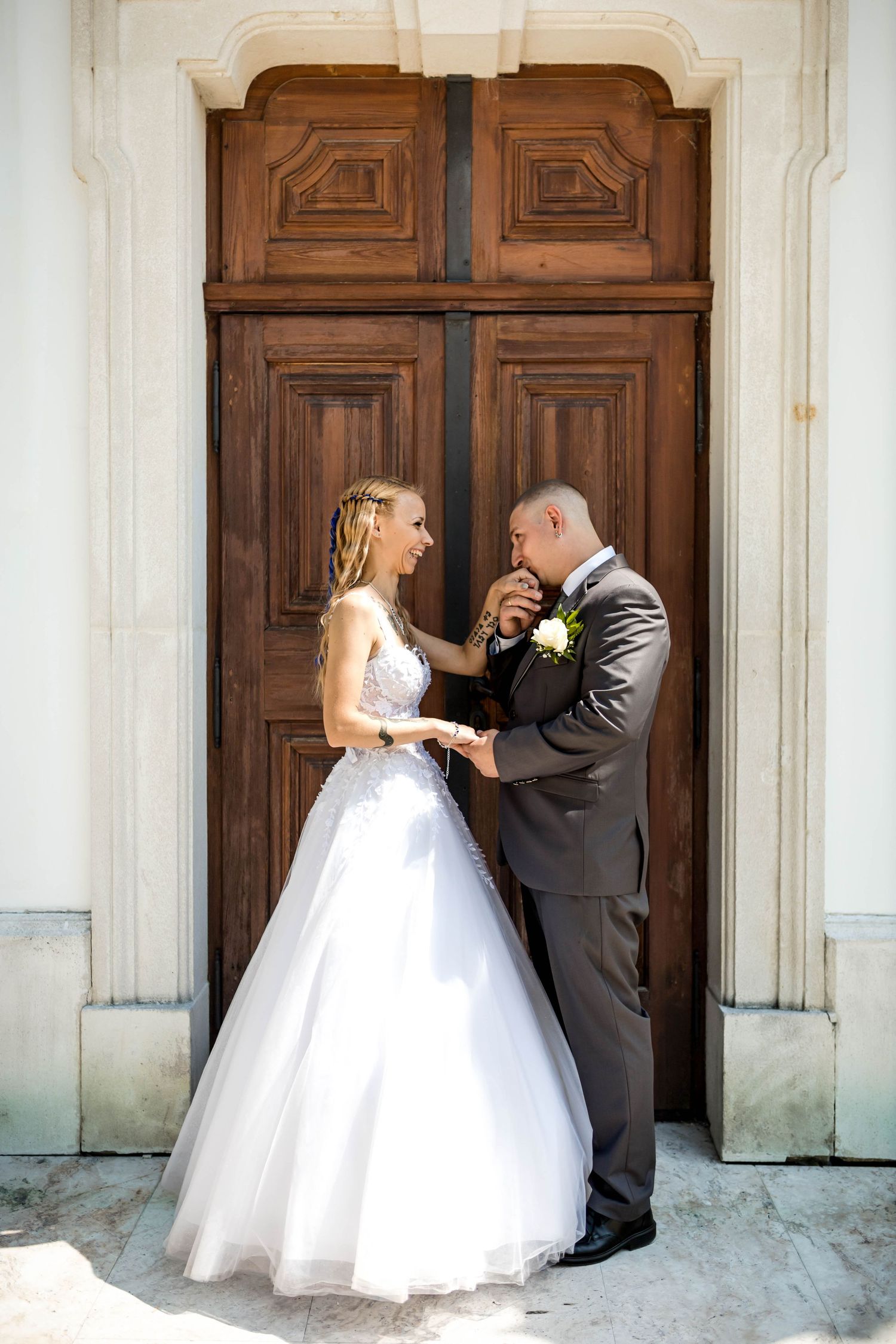 A wedding couple shares an intimate dance sequence in front of ornate wooden doors at a historic venue.