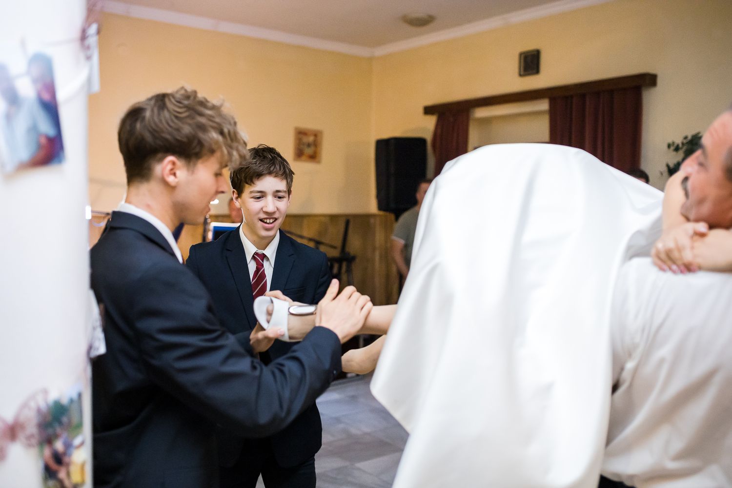 Wedding guests engage in lively conversation during a reception in a room with yellow walls.