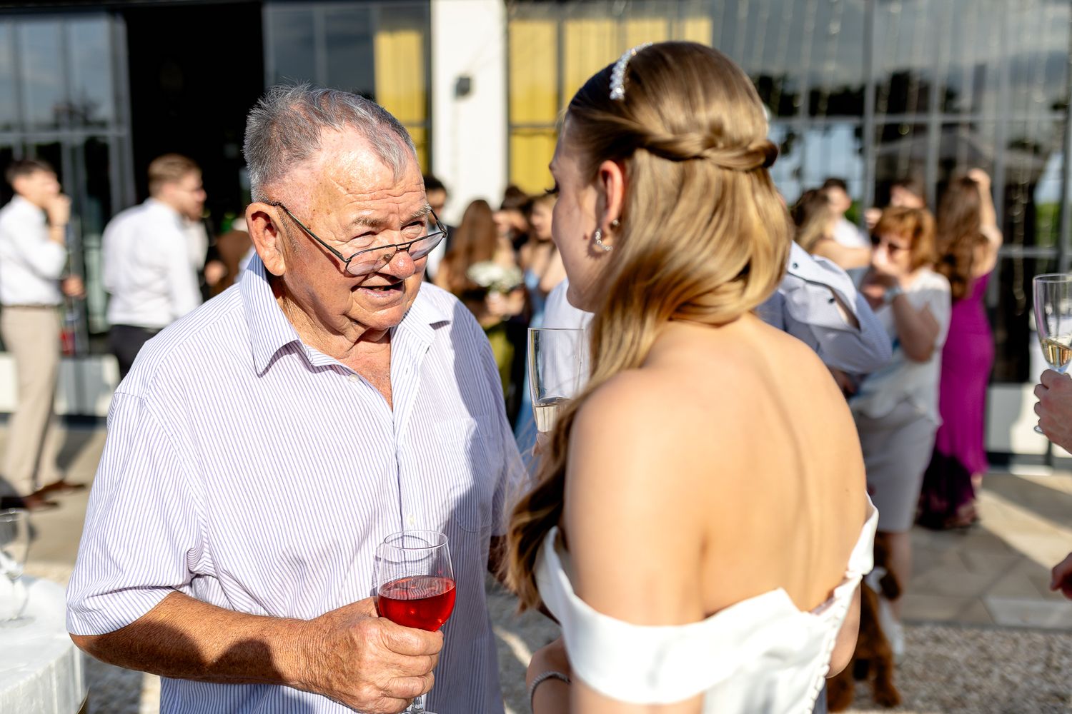 Wedding guests mingling during outdoor reception near modern building.