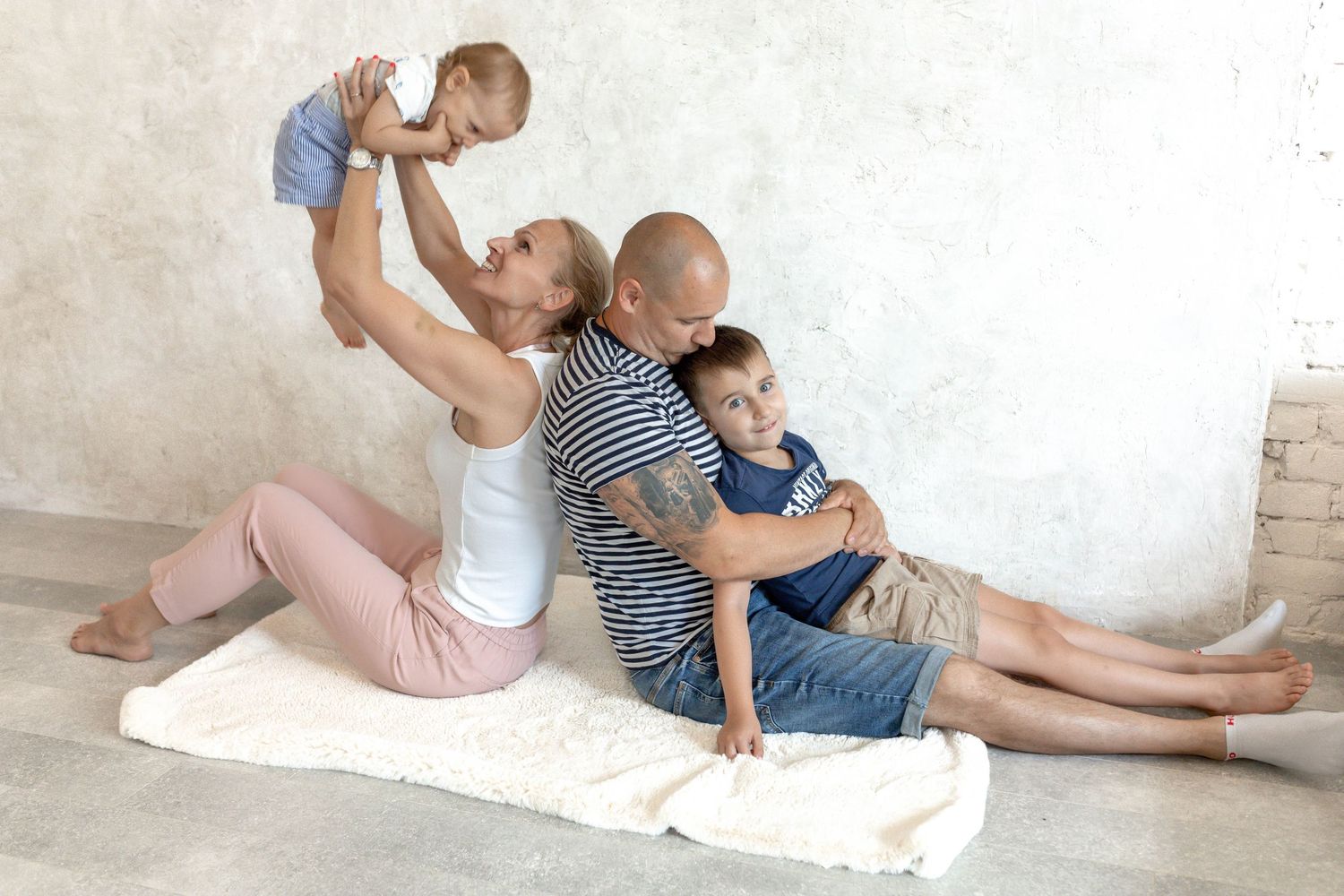 Casual family photoshoot showing intimate moments on light colored floor.