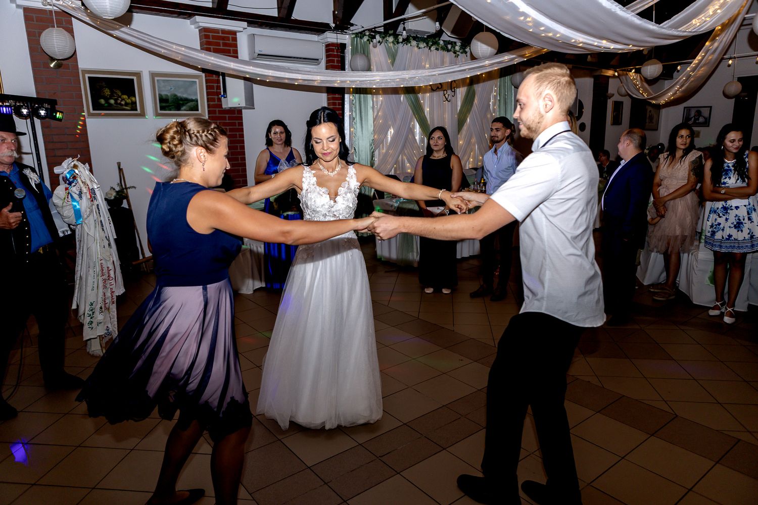 Couples dancing together at a wedding reception with decorative white fabric draping from the ceiling.