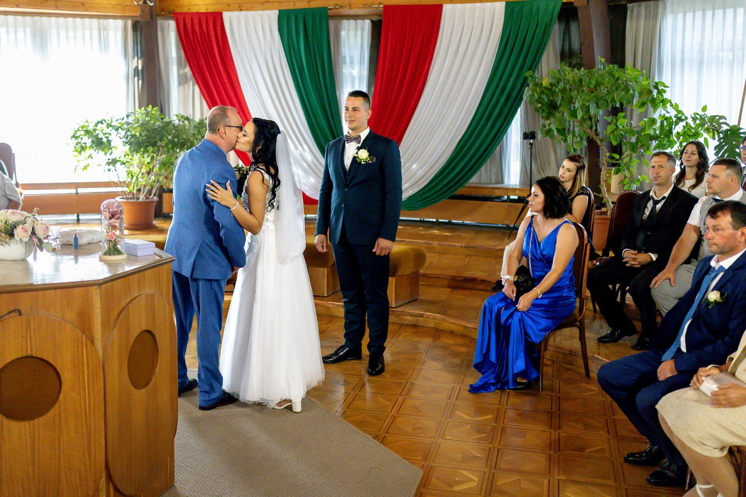 A row of wedding ceremony photos showing wooden church pews decorated with colorful red, green and white draping fabric.