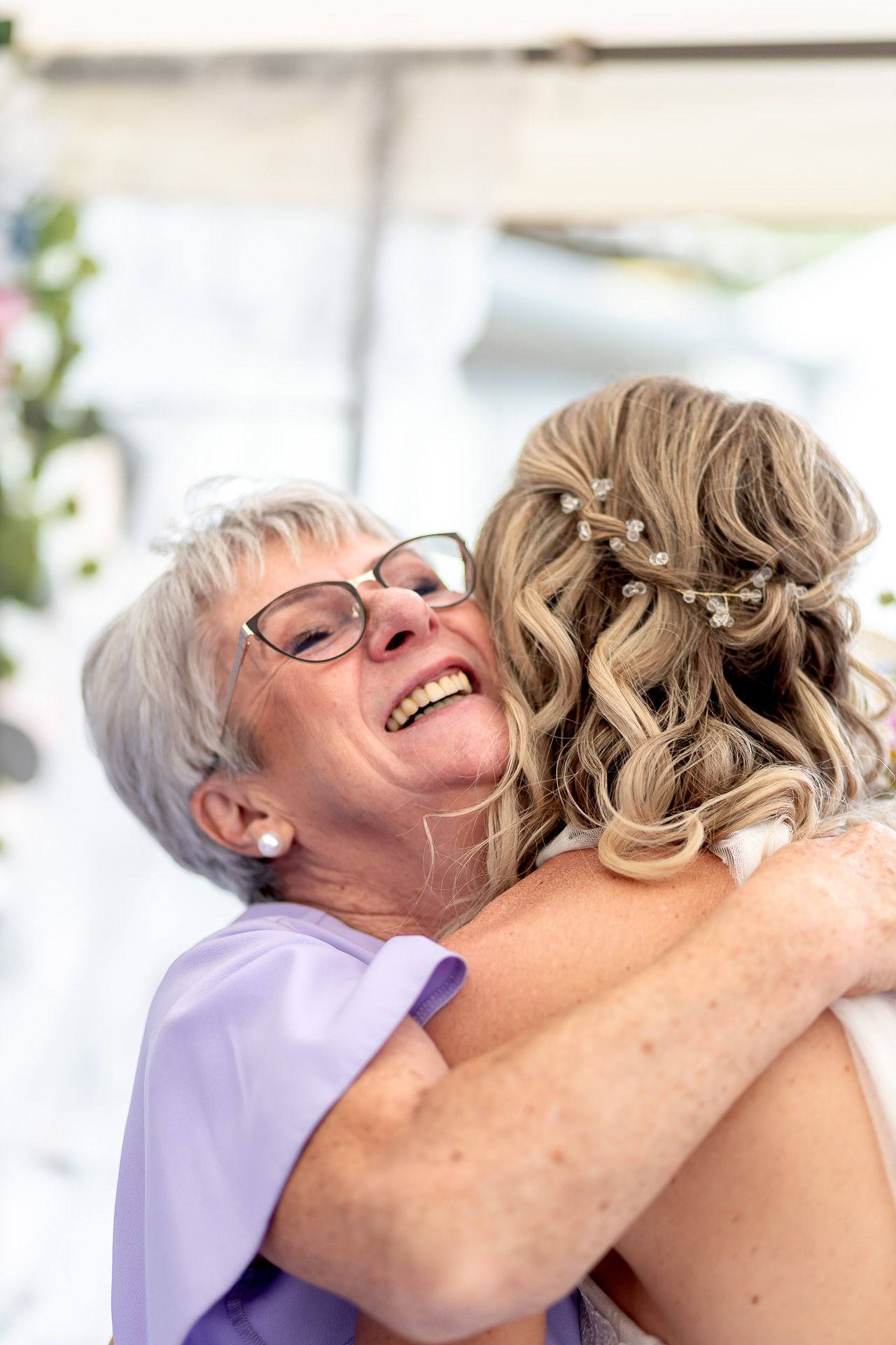 Two people share a warm embrace filled with joy and laughter in a bright, sunlit room.