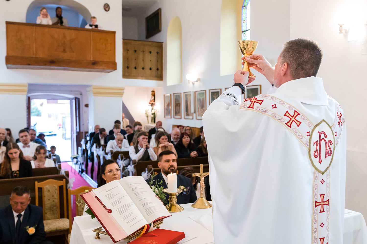 A group of clergy members in white robes stand at the altar during a religious ceremony at church.