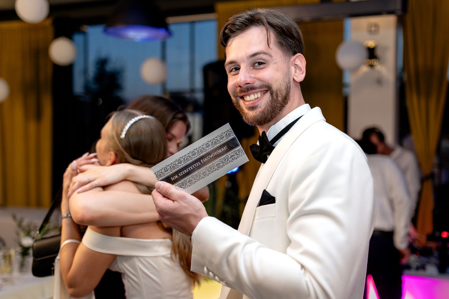 Wedding guests dance and celebrate on an illuminated dance floor under elegant chandeliers.