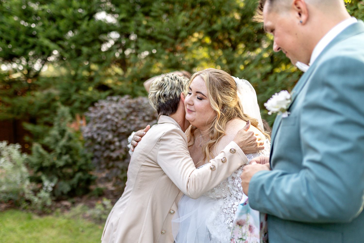 A couple shares romantic moments in an outdoor garden setting wearing formal wedding attire.