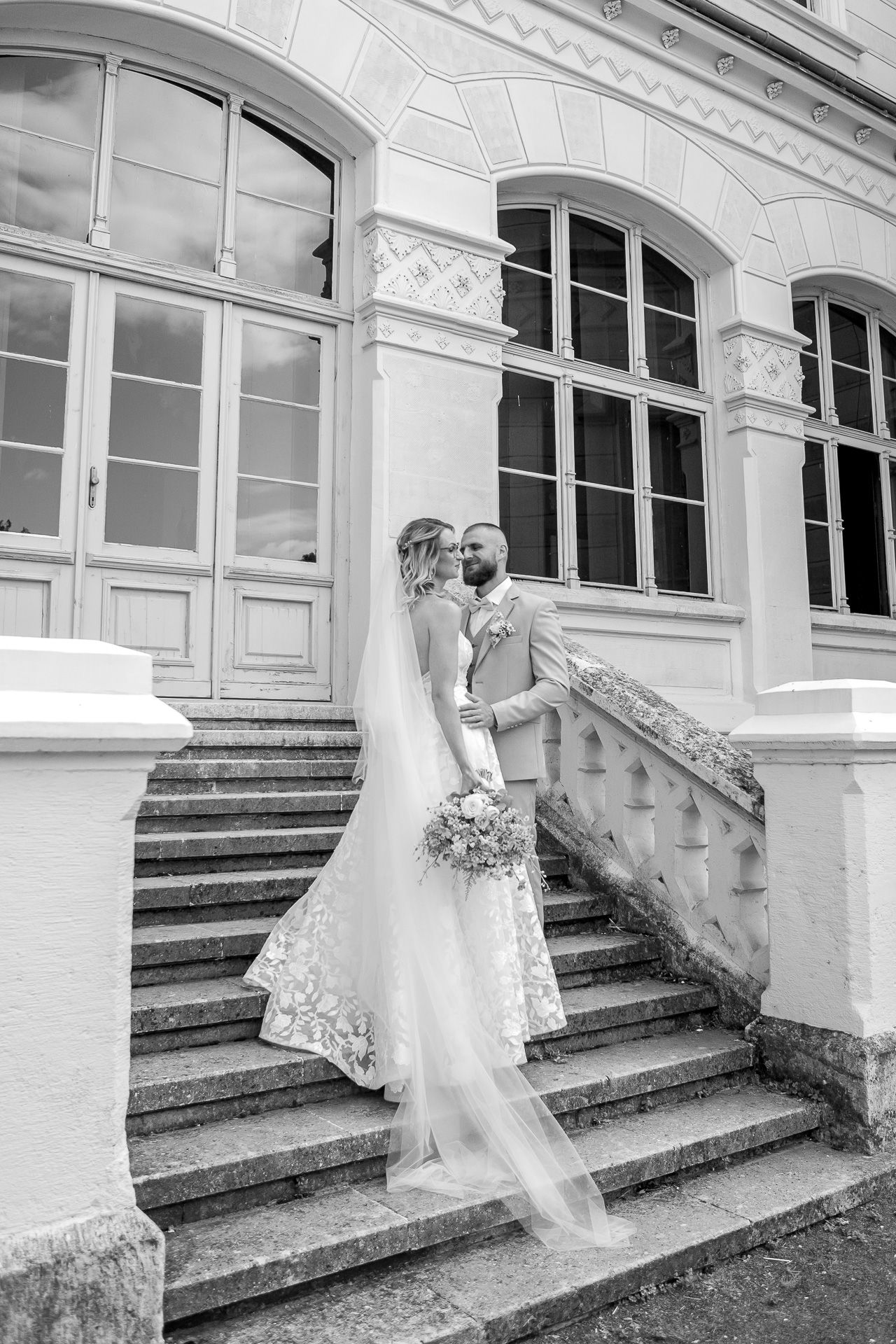 A romantic black and white wedding photo sequence showing a couple embracing on elegant stone steps of a historic building.