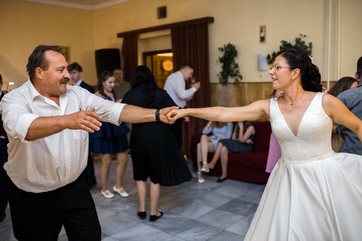 People dancing in pairs at a formal event with white and black attire in an elegant ballroom setting.