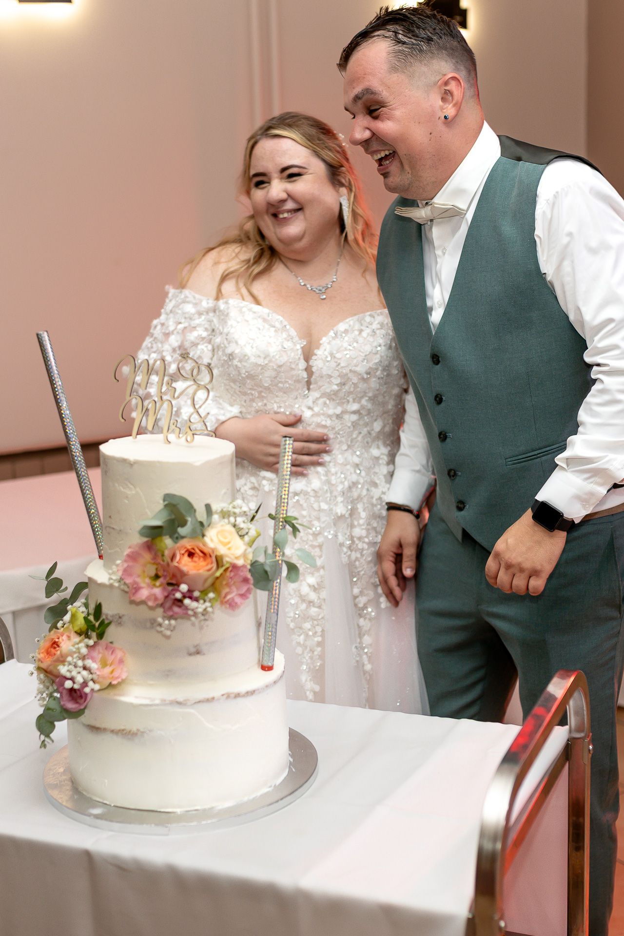 Newlywed couple sharing a sweet moment while cutting their elegant white wedding cake together.