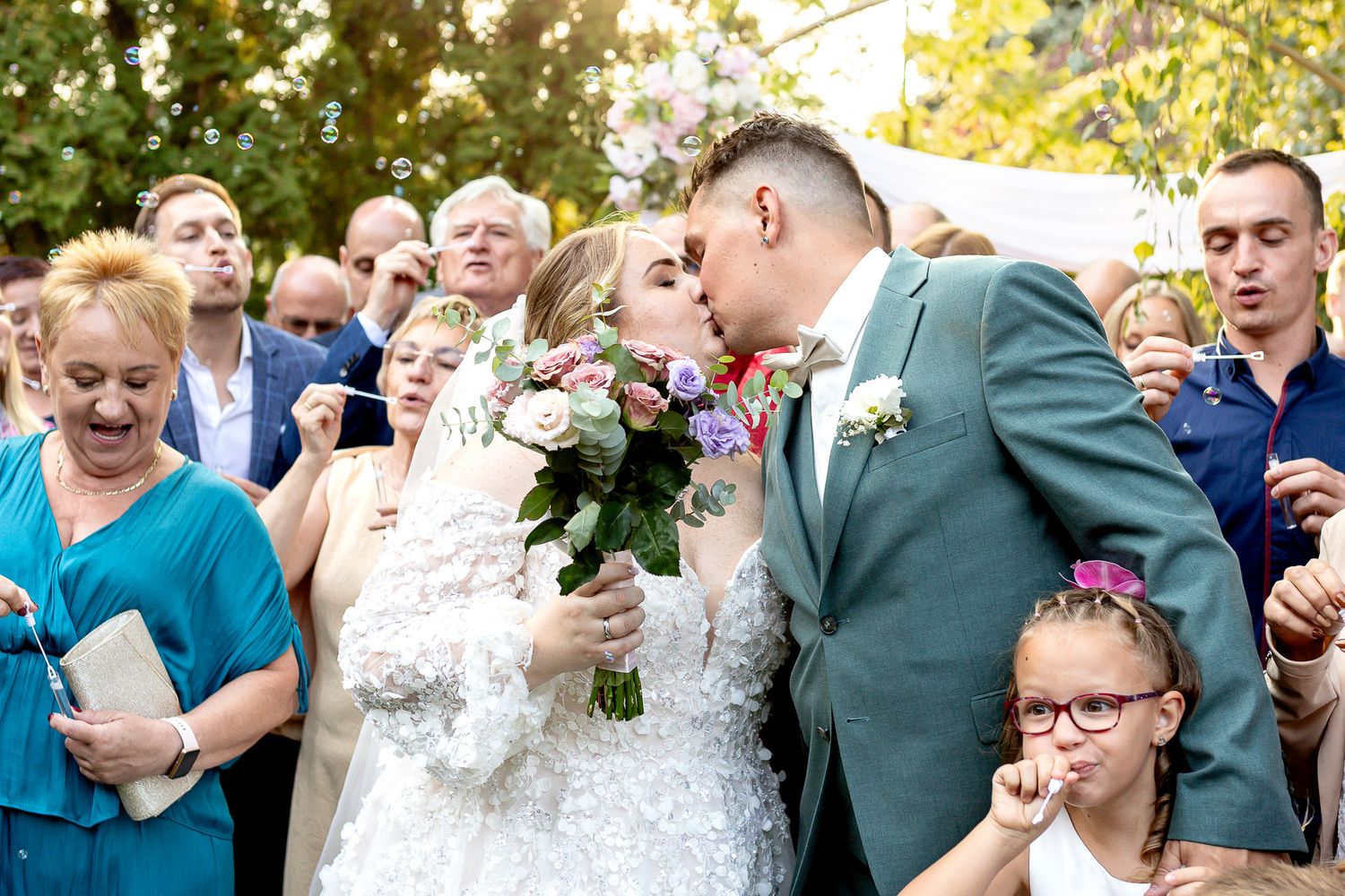 Wedding guests celebrate and share joyful moments during an outdoor reception in a garden setting.