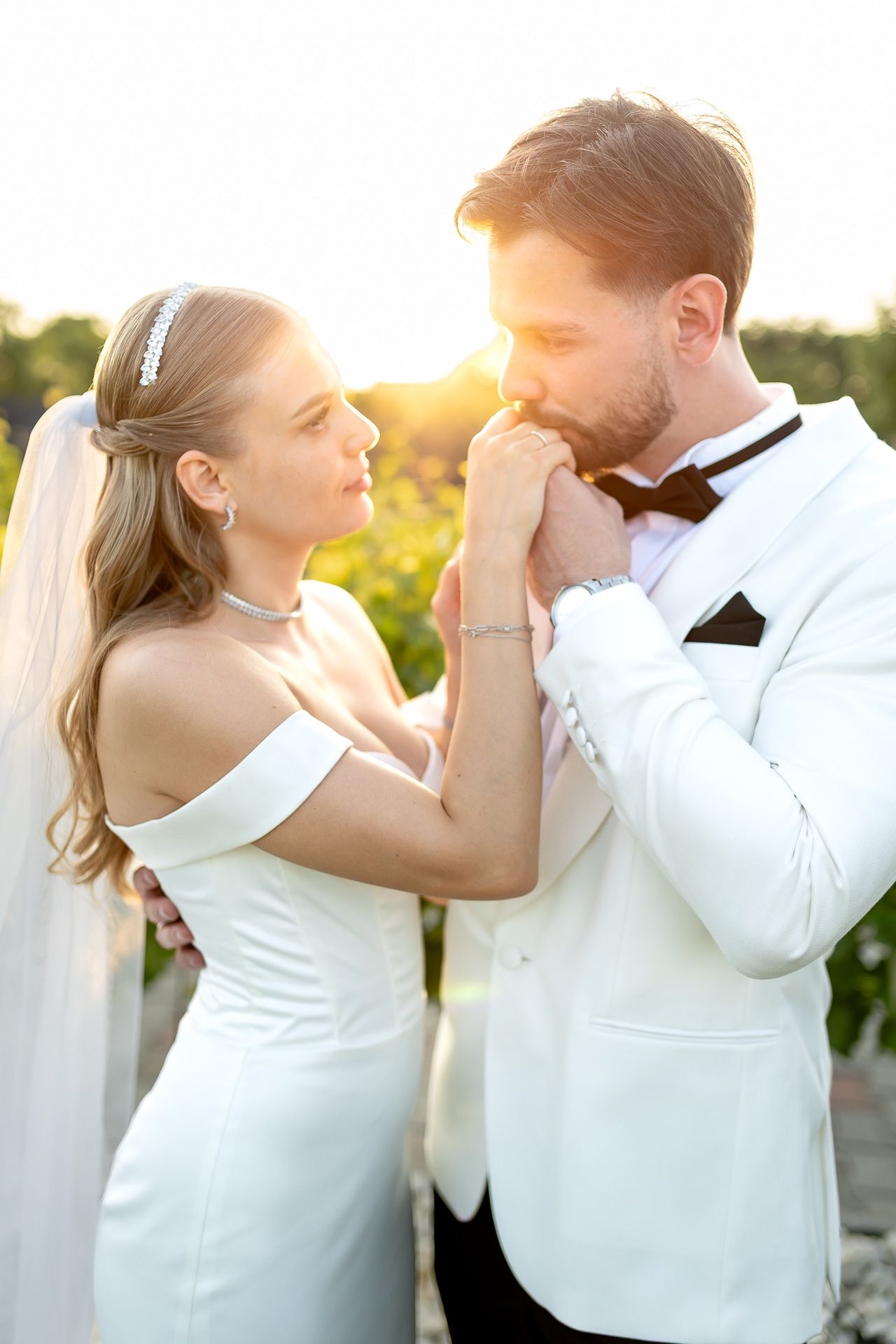 Romantic wedding couple embraces in a sun-drenched vineyard during golden hour.