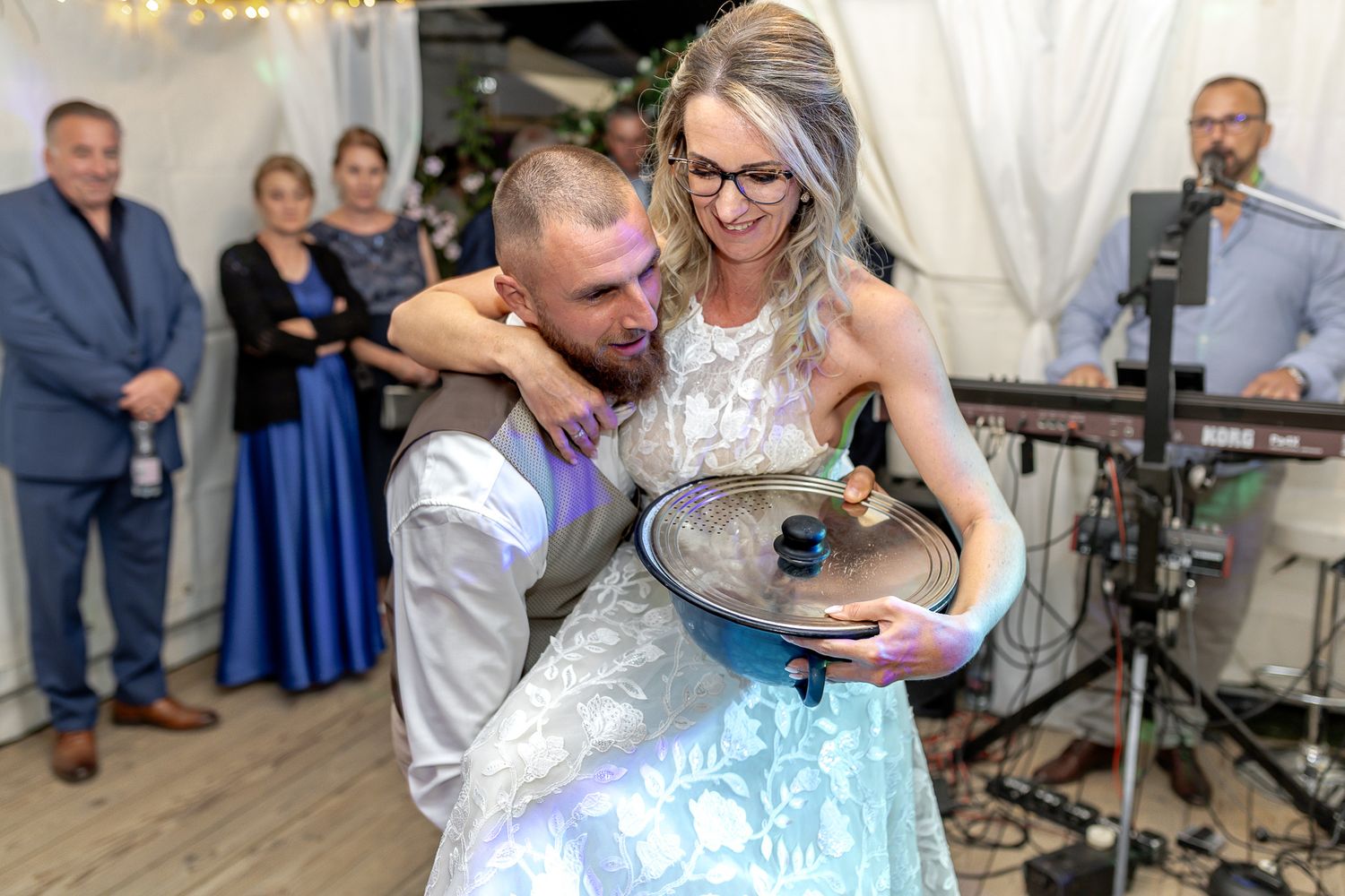 Couples share romantic dances at a wedding reception under twinkling lights and white tent decor.