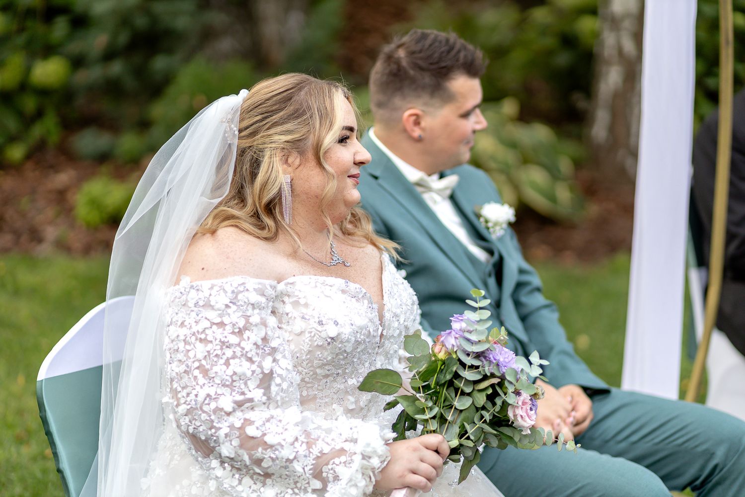 Bride and groom share intimate moments during their outdoor wedding ceremony under white gazebo.