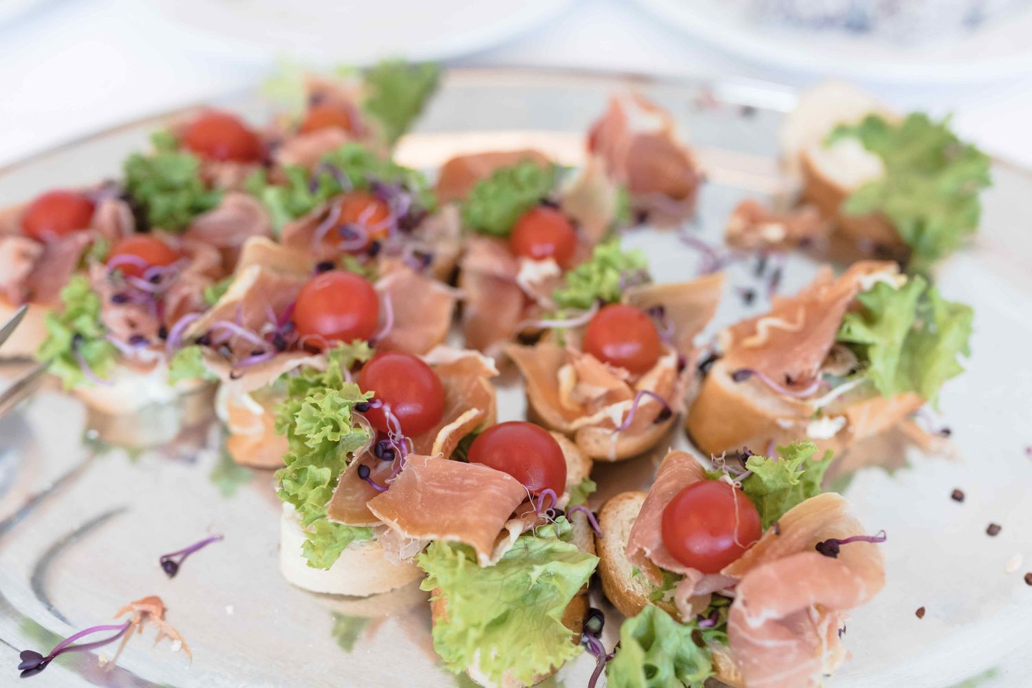 Fresh prosciutto and mushroom bruschetta appetizers arranged on lettuce leaves with garnish.