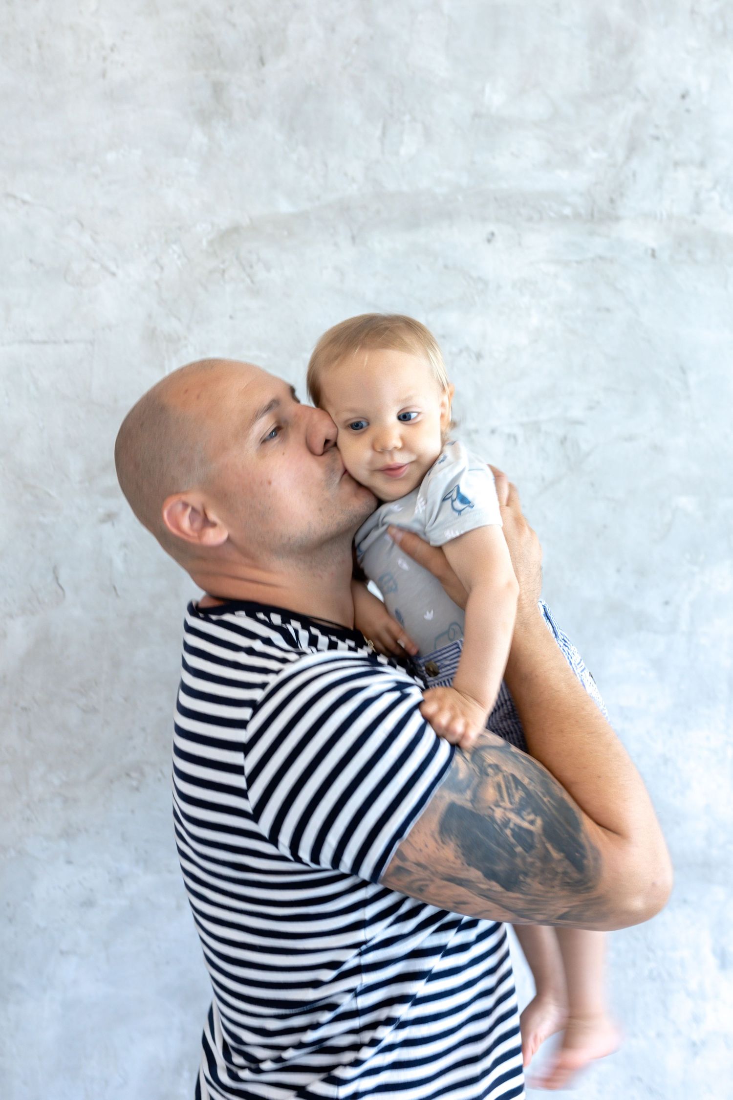 Sweet family interactions captured against a minimalist white wall background.
