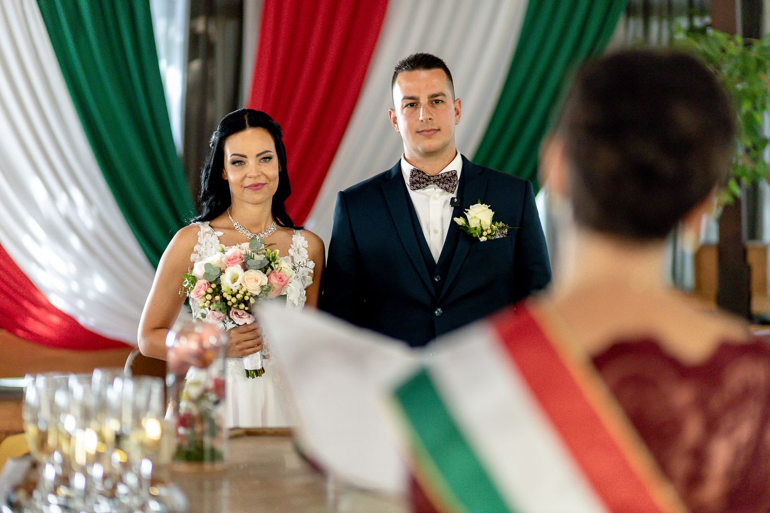 Wedding ceremony with Italian flag decorations hanging in the background as couple celebrates their special day.