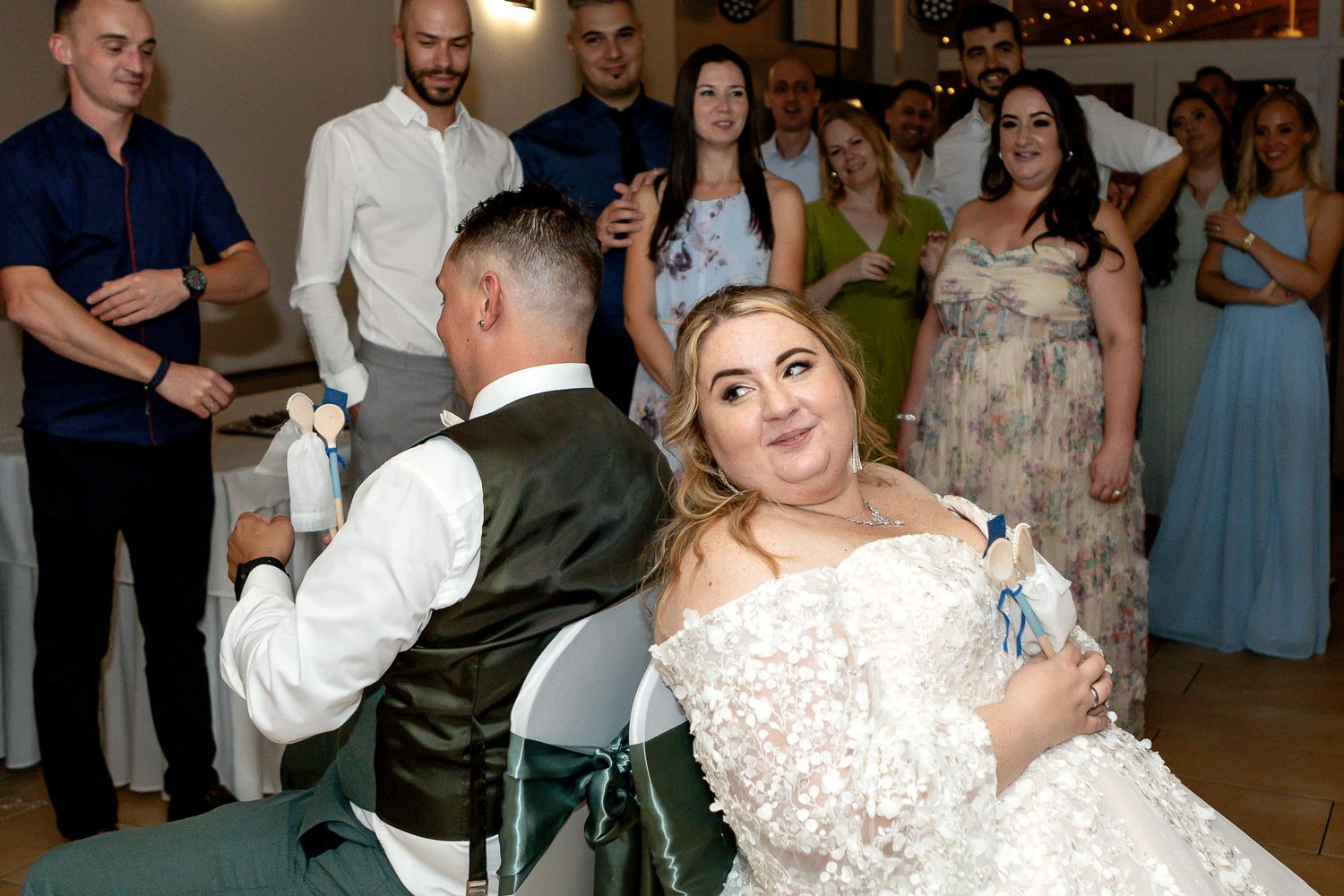Wedding celebration with couples dancing together on a dimly lit indoor dance floor.