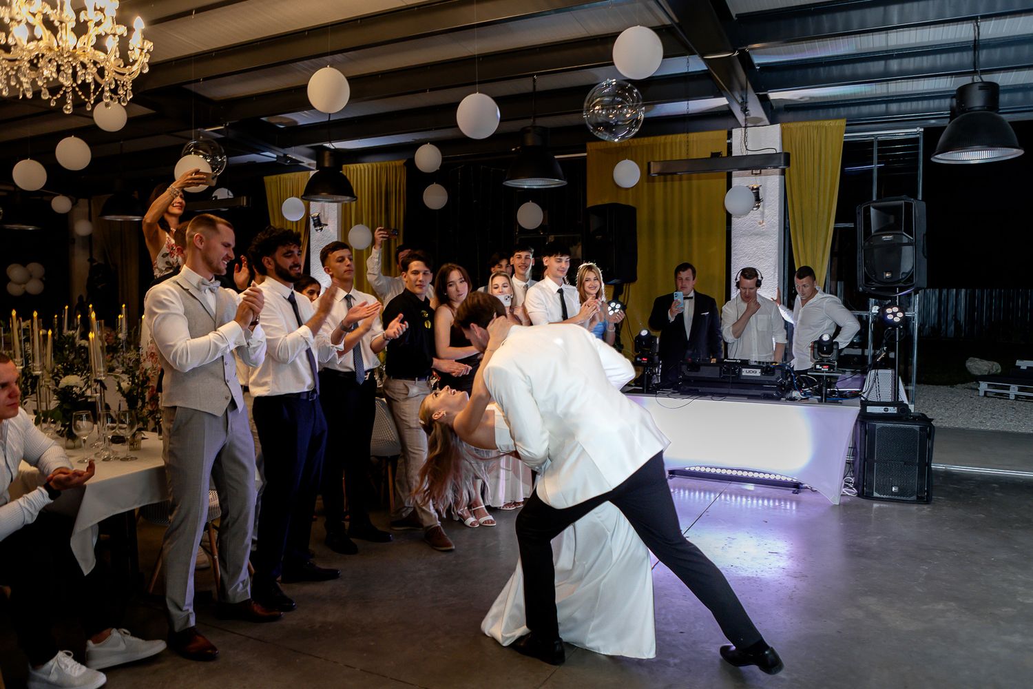 Wedding party members perform choreographed dance moves in a dimly lit reception venue.