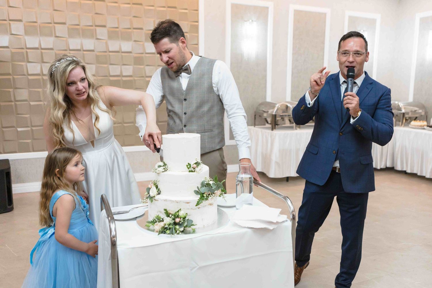 A wedding celebration in a bright reception hall with couples dancing and enjoying themselves in formal attire.