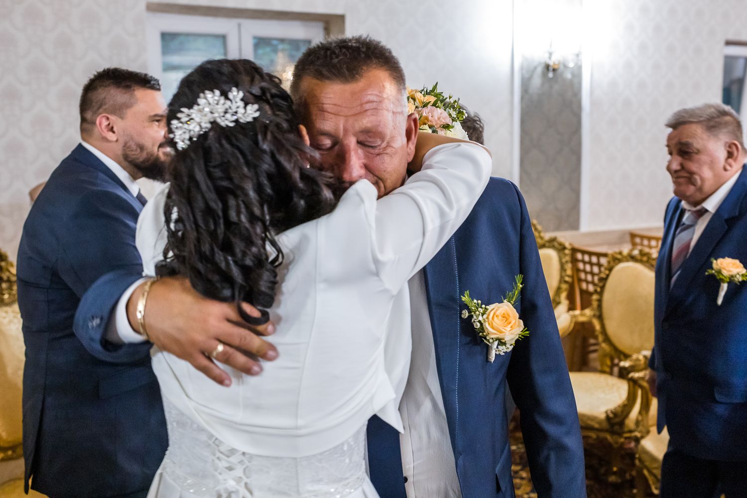 Wedding guests embrace and congratulate each other during an emotional reception celebration.