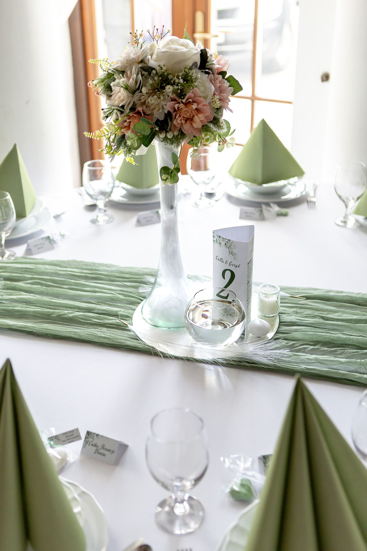 Elegant table settings with mint green napkins and white floral centerpieces arranged for a formal dining event.